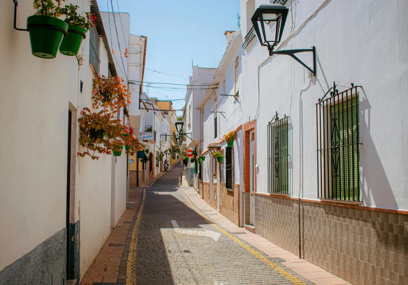 Witte straat in Estepona met bloempotten en traditionele gevels